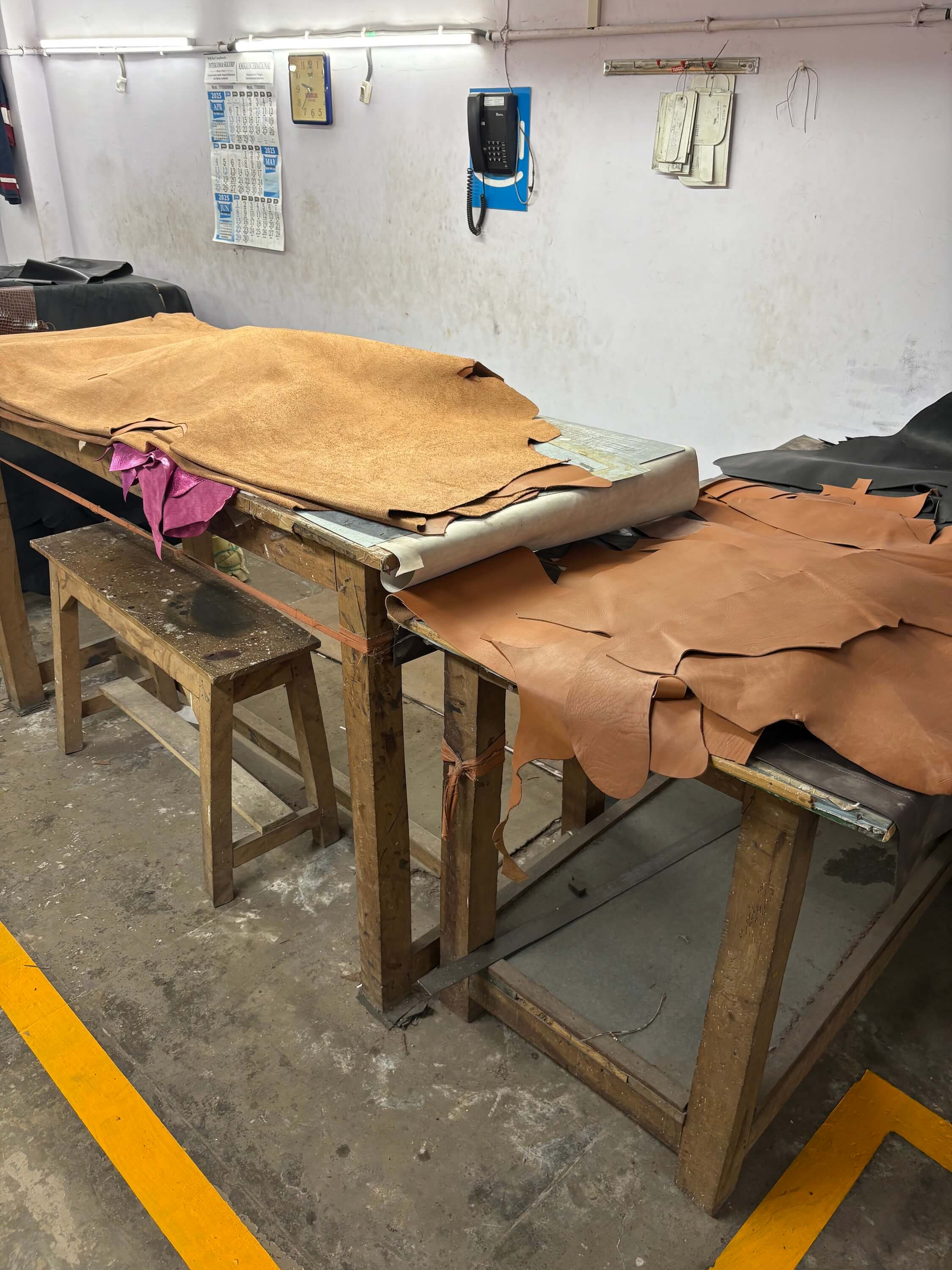 Atelier en Inde où sont fabriqués les sacs Charlay Stone, avec des peaux de cuir posées sur la table de découpe dans un environnement artisanal