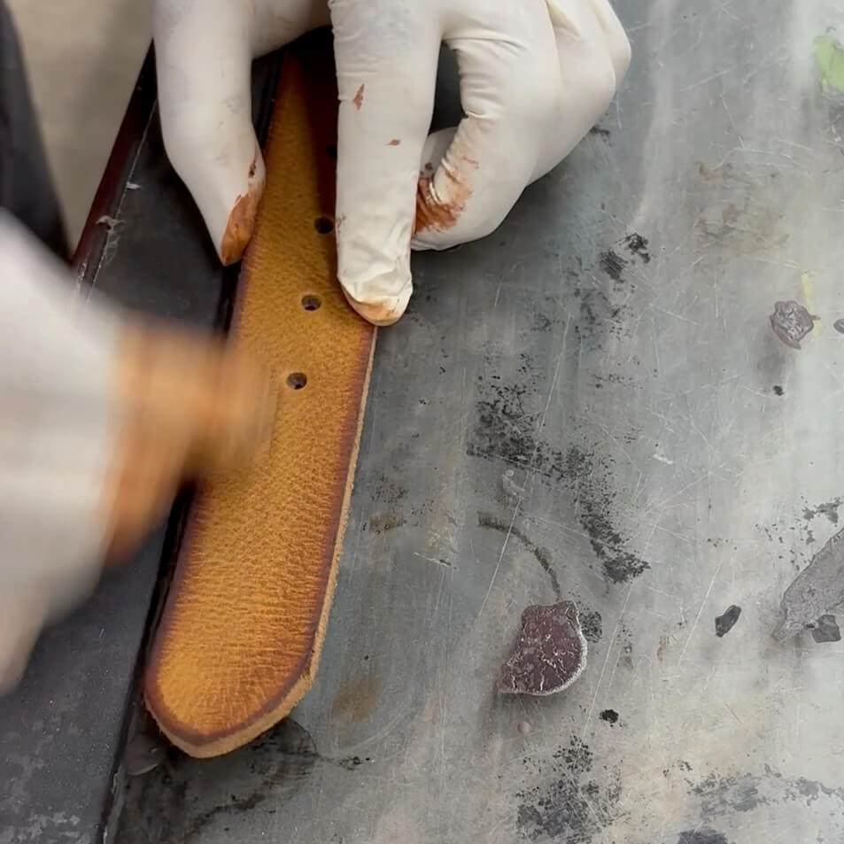 Artisan appliquant la teinture sur une ceinture en cuir dans l’atelier Charlay Stone, démonstration du savoir-faire artisanal